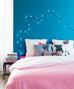 Bedroom with string light house headboard blue walls colorful bedding and pillows